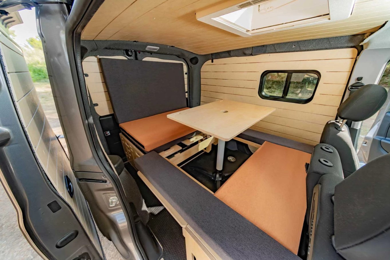 interior de una furgoneta con un asiento corrido y una mesa de madera