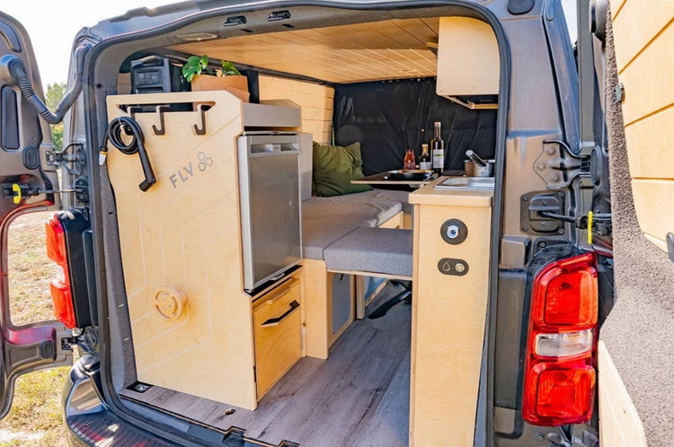 interior de un van equipado con zona de cocina y cama