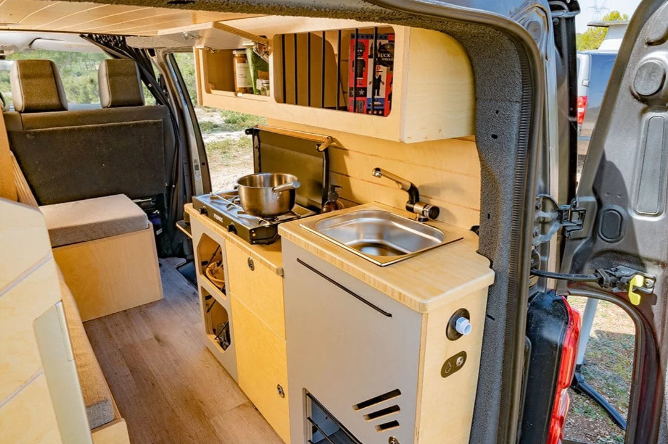 Zona de cocina de un VAN equipada con un fregadero cerca de la puerta trasera