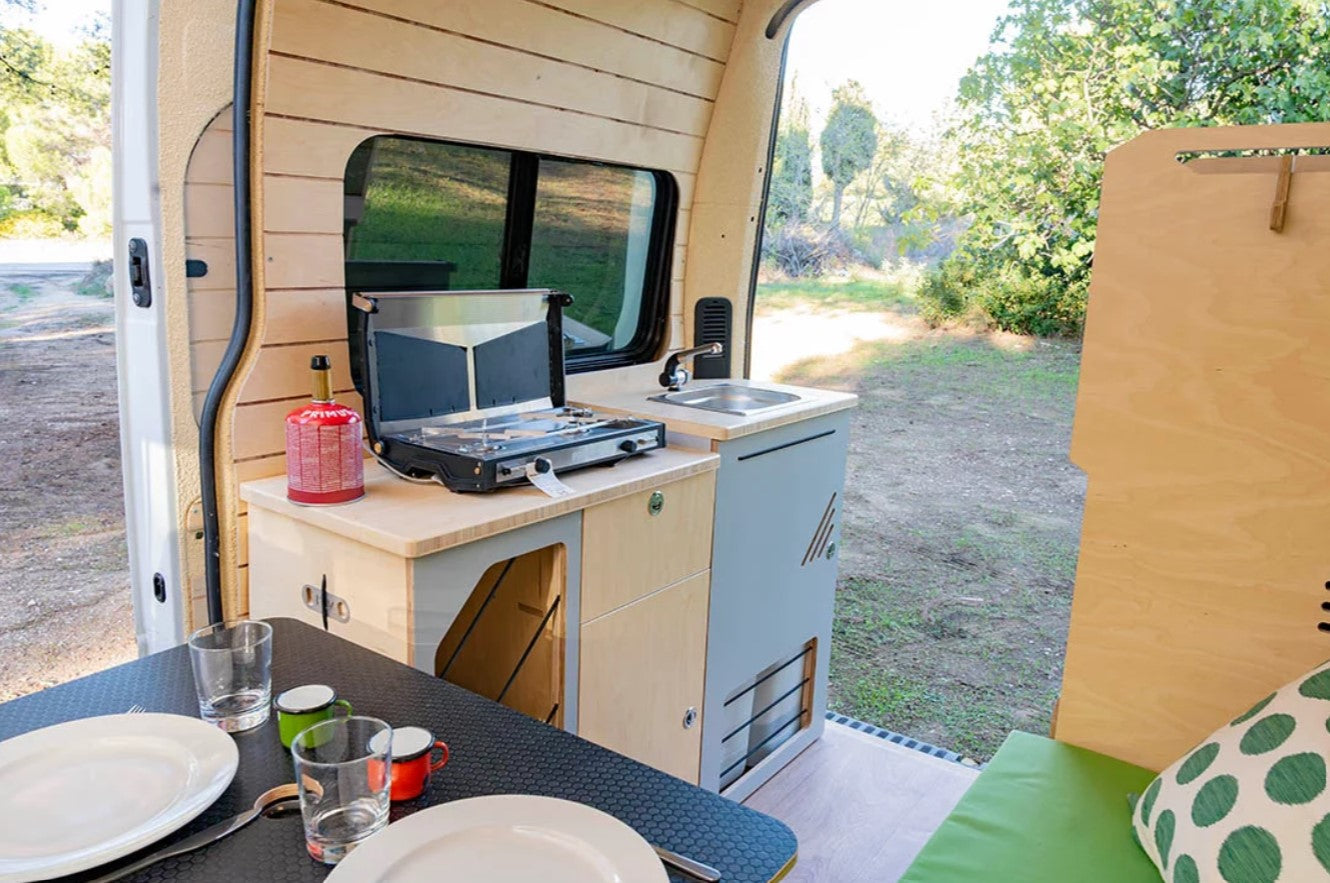 Van equipada con una zona de cama y cocina y una ventana lateral