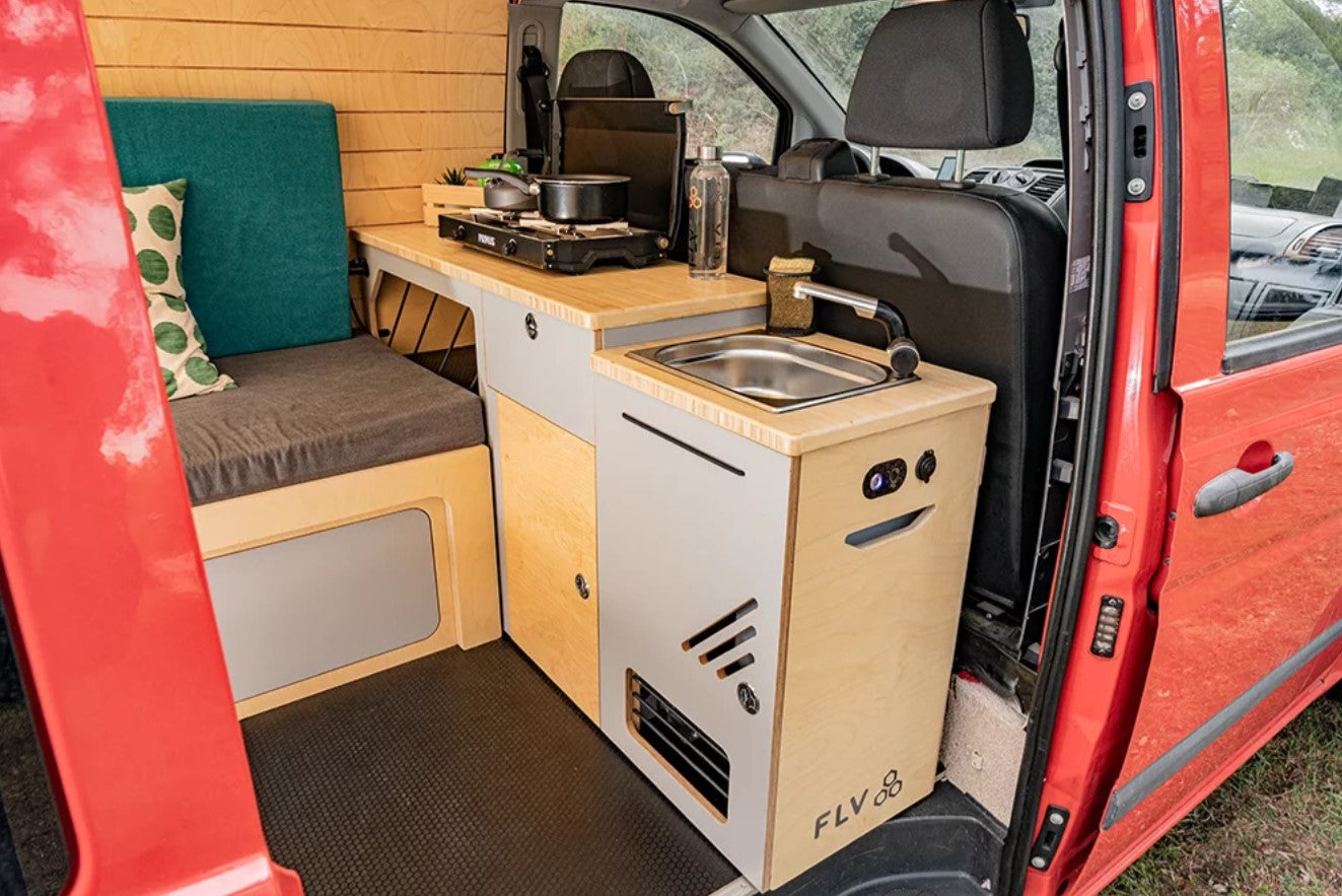 Interior de una furgoneta transformada con módulo de cocina y fregadero