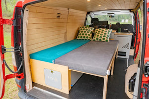 acondicionada en madera en un van rojo con la cama desplegada