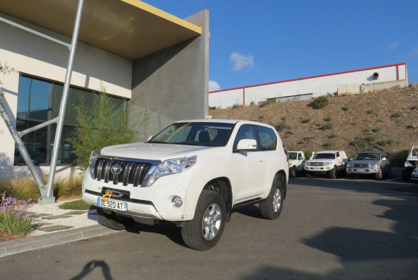 land cruiser 150 blanco aparcado en una acera 