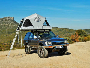 Toyota V8 frente a una colina con una carpa en el techo