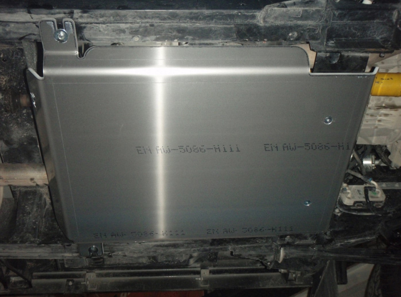 Protección en aluminio fijado debajo de un vehículo con escritura en él
