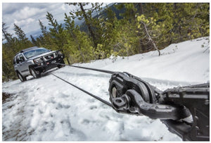 Nissan en la nieve remolcado por un cabrestante unido a un grillete warn