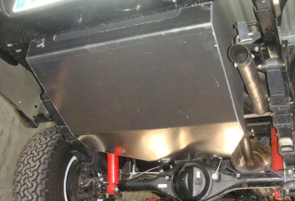 depósito de acero montado bajo un vehículo con amortiguadores rojos
