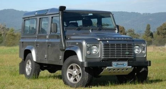 land rover defender 110 verde en la hierba con un snorkel negro