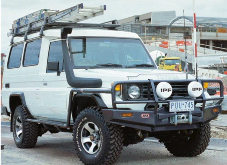 Land Cruiser 76 blanco con snorkel y escalera en la baca